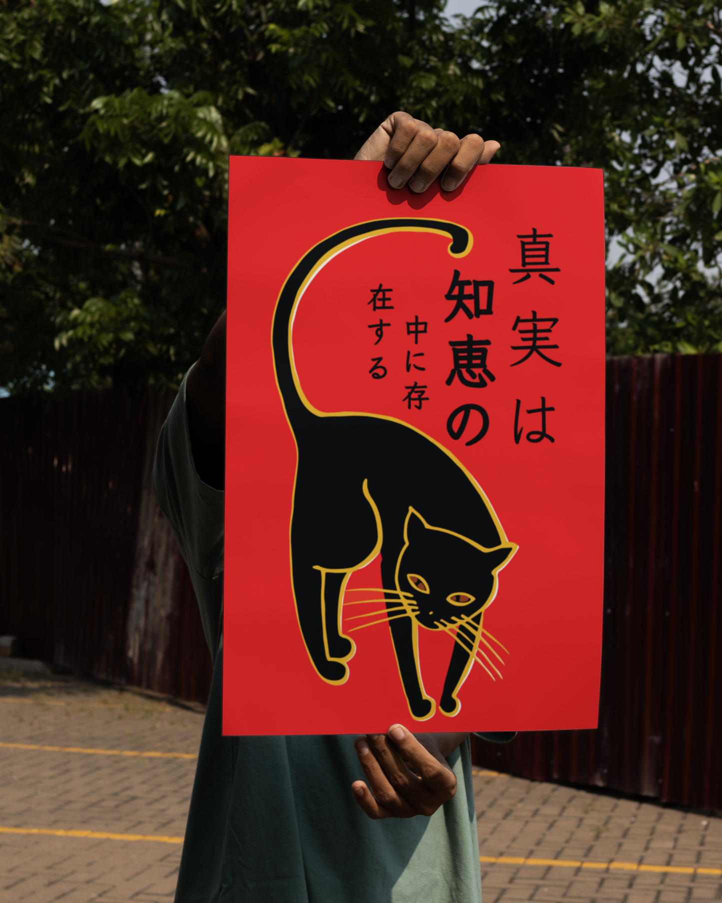 Unframed Japanese cat print – striking red and black feline poster with kanji calligraphy, held outdoors
