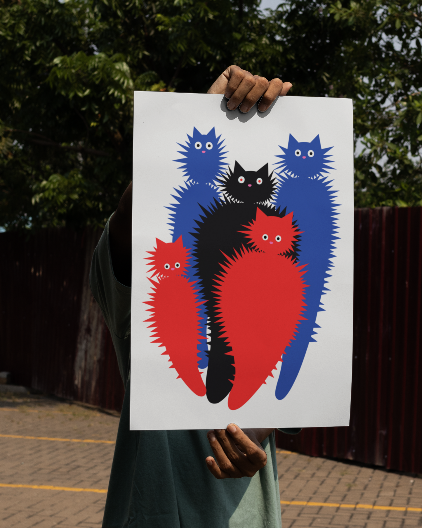 Unframed Creatures abstract cat print – surreal spiky feline poster in a bold red, blue, and black color scheme, held outdoors